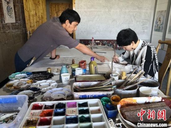 圖為2020年8月下旬，敦煌“80后”畫家張杰龍(左)在為云南麗江“學(xué)生”莫北講解敦煌壁畫的繪畫技巧。　馮志軍 攝