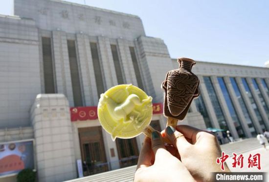2021年7月30日，游客手拿“銅奔馬”“彩陶瓶”造型的雪糕，在甘肅省博物館前拍照打卡。　高展 攝