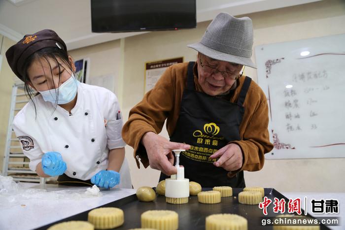 當日，受邀參加活動的臺胞臺屬代表、兩岸婚姻及子女、在甘臺商代表等歡聚一堂。圖為77歲的在甘臺胞潘天鑒制作月餅。九美旦增 攝