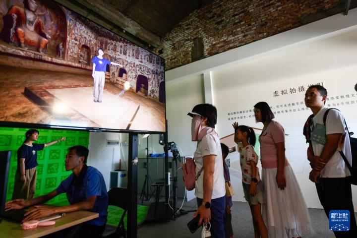 7月22日，游客體驗(yàn)“尋境敦煌——數(shù)字敦煌沉浸展”后，在虛擬演播廳拍攝一段真人與洞窟虛擬場景交互的視頻。新華社記者 郎兵兵 攝</p>
<p>